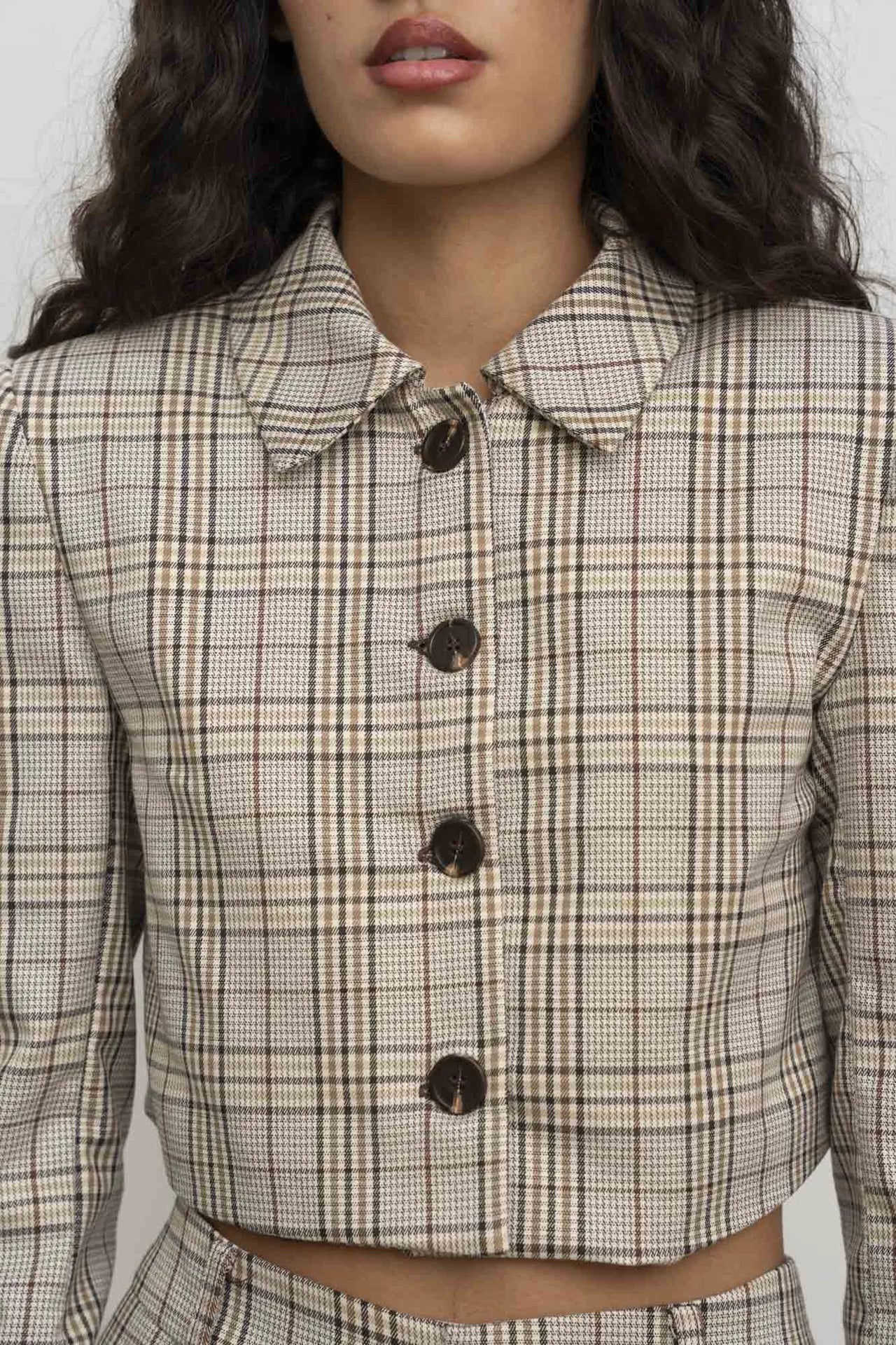 Détail sur la Veste Courte Femme à Carreaux Chic – Style Moderne, montrant les boutons contrastés et le motif à carreaux.