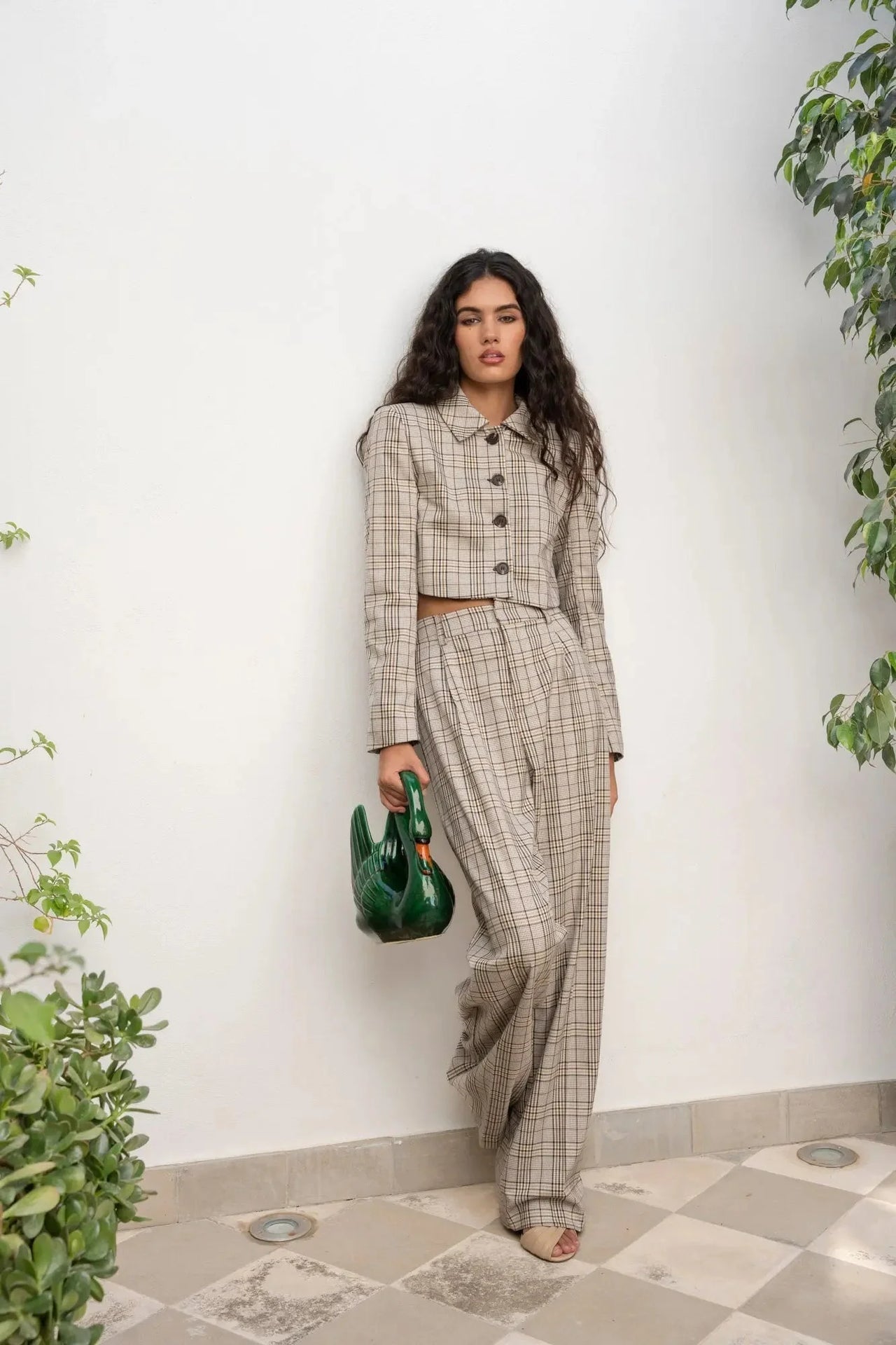 Femme posant avec la Veste Courte Femme à Carreaux Chic – Style Moderne, accompagnée d'un pantalon coordonné, dans un cadre élégant.