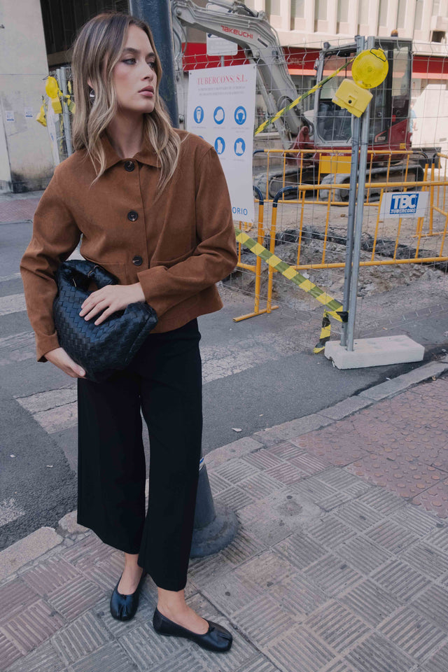 Modèle portant une veste courte élégante coupe droite marron effet suède en polyester extensible, avec un look décontracté, idéale pour une sortie en ville. Veste daim femme.