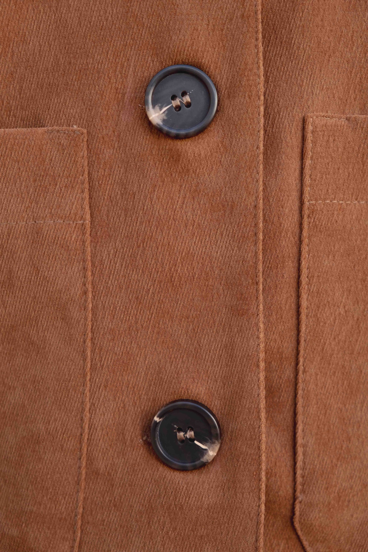Gros plan sur les boutons d'une veste courte élégante coupe droite marron effet suède, offrant une finition élégante et contemporaine. Veste daim femme.