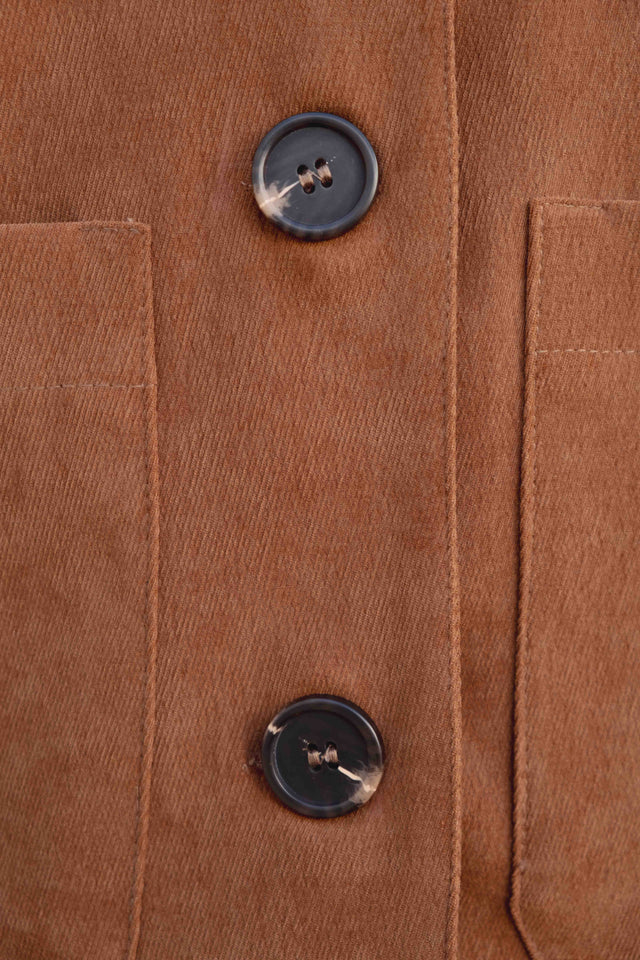 Gros plan sur les boutons d'une veste courte élégante coupe droite marron effet suède, offrant une finition élégante et contemporaine. Veste daim femme.