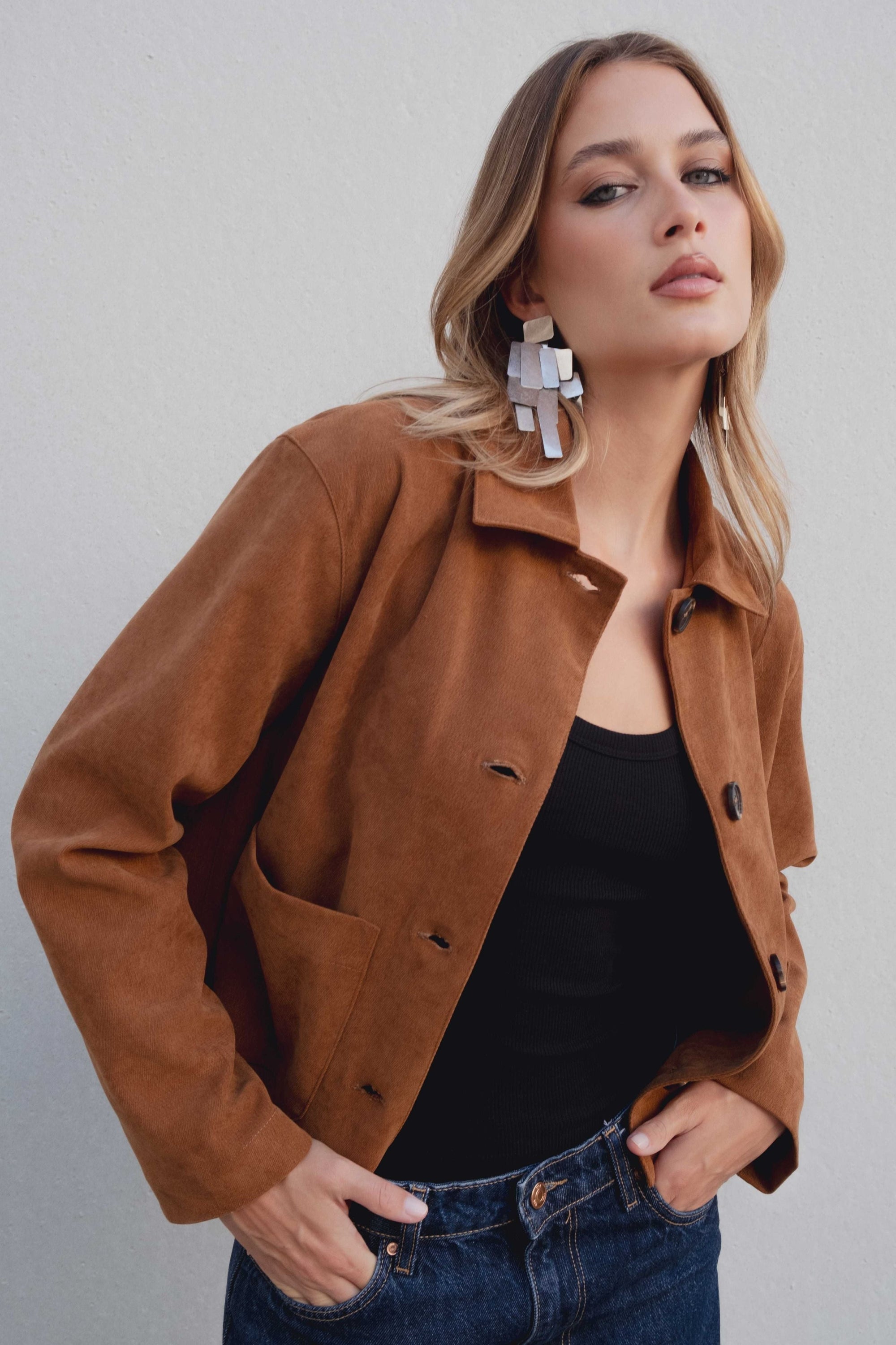 Zoom sur une veste courte élégante coupe droite marron effet suède portée par un modèle, mettant en valeur le manteau et le look moderne. Veste daim femme.