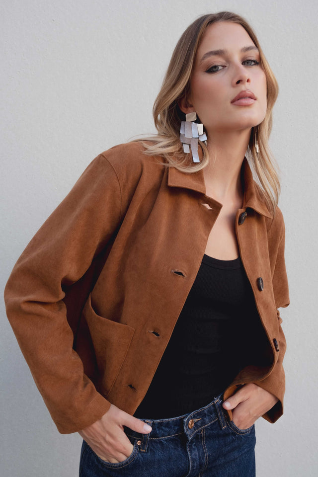 Zoom sur une veste courte élégante coupe droite marron effet suède portée par un modèle, mettant en valeur le manteau et le look moderne. Veste daim femme.
