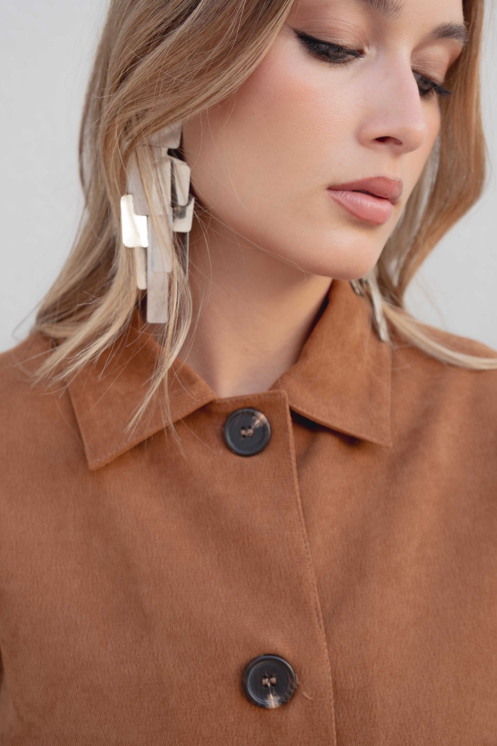 Détail sur le col d'une veste courte élégante marron effet suède, mettant en avant le design soigné et les boutons. Veste daim femme.